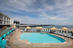 a swimming pool with chairs and umbrellas and the ocean at Dream Inn Santa Cruz in Santa Cruz