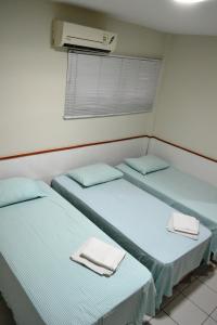 two beds in a room with towels on them at Hotel Itapoã in Teresina