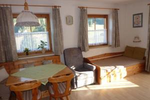 a living room with a bed and a table and a table and chair at Haus Moosanger in Oberau