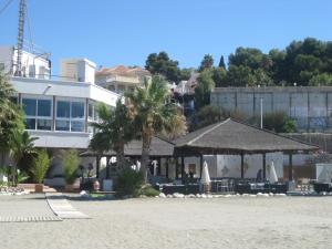ein Hotel am Strand mit Liegestühlen und Sonnenschirmen in der Unterkunft Apartamento en Villa con Piscina in Málaga