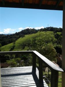 einen Balkon mit Blick auf einen grünen Hügel in der Unterkunft Chalé Serra do Luar in Santo Antônio do Pinhal