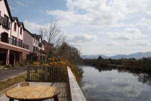 a wooden table and chairs next to a river at Grove Lodge Holiday Homes in Killorglin