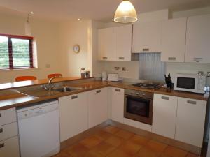 a kitchen with white cabinets and a sink and a microwave at Grove Lodge Holiday Homes in Killorglin