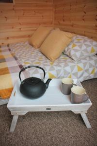 a tea kettle and two cups on a tray next to a bed at Howe of Torbeg in Ballater
