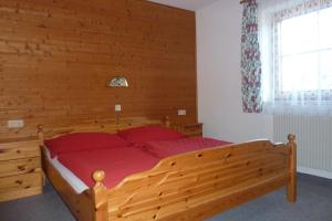 Schlafzimmer mit einem Holzbett mit roten Kissen in der Unterkunft Haus Moosanger in Oberau