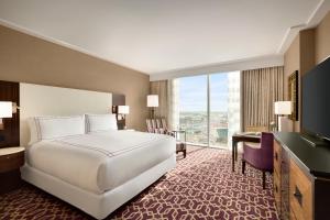 オースティンにあるFairmont Austin Gold Experienceのベッドと大きな窓が備わるホテルルームです。