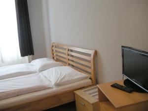 a bedroom with a bed and a desk with a television at Pension Schottentor in Vienna