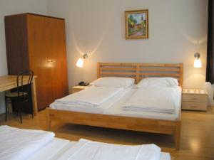 a bedroom with two twin beds and a desk at Pension Schottentor in Vienna