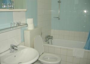 a bathroom with a toilet and a sink and a tub at Pension Schottentor in Vienna