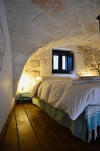 1 dormitorio con 1 cama en una pared de piedra en La Violetta Ostuni, en Ostuni
