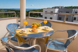 a table and chairs on a balcony with drinks and fruit at Apartments Flora in Premantura