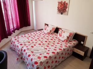 a bedroom with a bed with a red and white blanket at Family Aparthotel Vintegra in Burgas