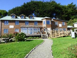 une grande maison en bois avec une pelouse dans l'établissement Hostal Mundo Nuevo, à Ancud