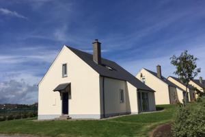 una casa bianca con un tetto nero sull'erba di Seamount Holiday Village a Courtown