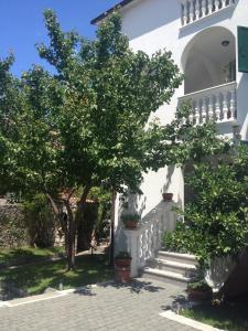 a white building with stairs and trees next to it at Apartmani Vukičević in Vodice