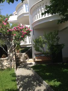 a building with a bench and pink flowers at Apartmani Vukičević in Vodice