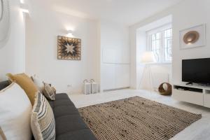uma sala de estar branca com um sofá e uma televisão em FLH Graça Cozy Flat em Lisboa