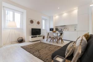 a white living room with a couch and a kitchen at FLH Graça Cozy Flat in Lisbon