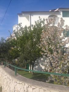 a white building with trees in front of a wall at Apartmani Vukičević in Vodice