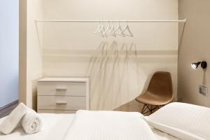 a bedroom with a white bed and a chair at Evel's Home Suites in Thessaloniki