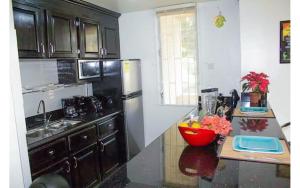a kitchen with black cabinets and a bowl of fruit on a counter at Coconut Shell At Turtle Towers in Ocho Rios