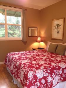 a bedroom with a bed with a red and white blanket at Carson's Kaloko Mountain Cottage in Kailua-Kona