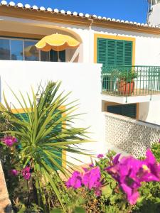 a house with a balcony with an umbrella and flowers at Casas da Vila in Luz