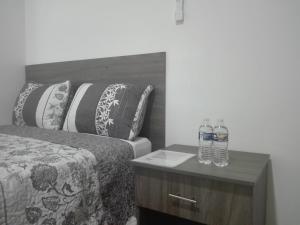 a bed with two bottles of water on a night stand at MV Suites Suc. Capilla in Monterrey