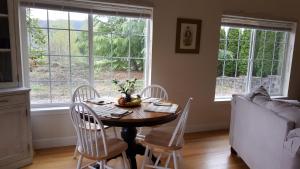 a dining room with a table and chairs and windows at Charming, Private Cottage in Myrtle Creek in Myrtle Creek