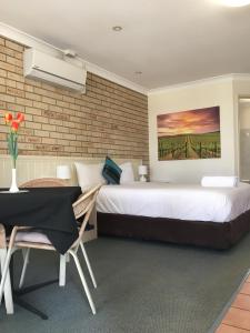 a bedroom with a large bed and a table and chair at Jolly Swagman Motor Inn in Goondiwindi