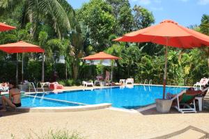 a swimming pool with umbrellas and people sitting around it at Wild Orchid Villa Krabi in Ao Nam Mao