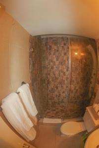 a bathroom with a shower with towels and a toilet at Beach Side Suite At Turtle Towers in Ocho Rios