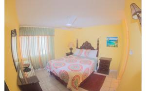 a bedroom with a bed with a white and pink bedspread at Sand Dreams at Turtle Towers in Ocho Rios