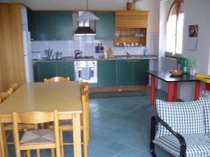 une cuisine avec des armoires vertes, une table et des chaises dans l'établissement L'Ambra, à Alghero