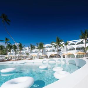 a resort swimming pool with a hotel in the background at SALA Samui Chaweng Beach Resort in Chaweng