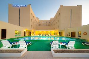 una piscina en un hotel con sillas blancas y un edificio en Best Western Sur, en Sur