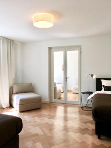 uma sala de estar com um sofá, uma cadeira e uma porta de vidro deslizante em VIADUKT Apartments em Zurique