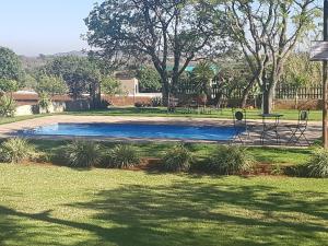 a swimming pool in a park with trees and grass at Marjaniek Wedding Venue & Guest House in Rietfontein