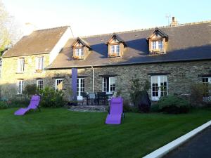 una casa con sillas de césped púrpura delante de ella en L'Anctovillière, en Anctoville
