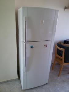 a white refrigerator in a room with a chair at Dimar1 Seaside Apartment in Paralia Dionysiou