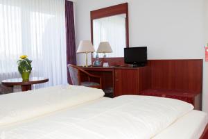 a hotel room with two beds and a desk with a television at Hotel Seeblick garni in Gartow