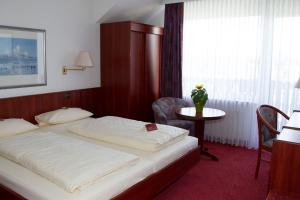 Schlafzimmer mit einem Bett, einem Tisch und einem Fenster in der Unterkunft Hotel Seeblick garni in Gartow