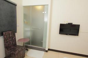 Habitación con ducha de cristal, silla y TV. en Sanyi Sakura Resort en Sanyi
