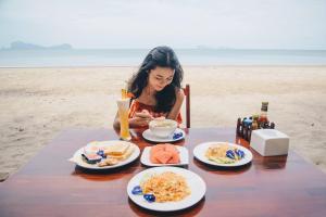 Eine Frau, die an einem Tisch mit Teller Essen sitzt. in der Unterkunft Yataa Spa and Resort in Ko Sukon