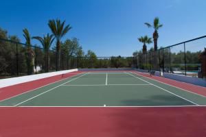 a tennis court with palm trees in the background at Hotel Klonos - Kyriakos Klonos in Aegina Town