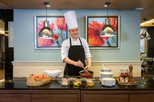a chef standing in a kitchen preparing food at Evergreen Place Siam by UHG in Bangkok