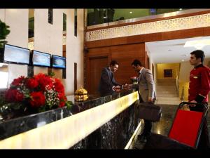 dos hombres parados en un mostrador en un vestíbulo en Revag Palace Hotel, en Sivas