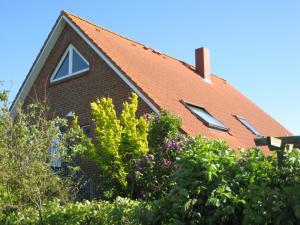 una casa con techo rojo y algunos arbustos en Haus Pistorius, en Büsum
