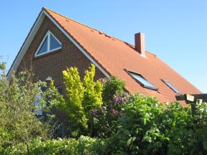 ein Haus mit rotem Dach und einigen Büschen in der Unterkunft Haus Pistorius in Büsum