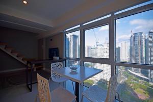 a dining room with a table and chairs and a large window at Victoria SOHO Suites in Manila